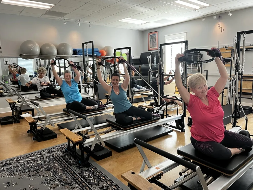Energetic group Pilates class at Dancing Hammock — clients smiling with arms raised